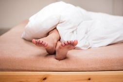 pies de mujer sobresalen de colcha sobre cama